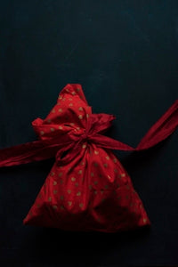 red and gold polka-dot drawstring pack on black surface