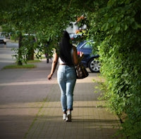 woman in blue denim jeans standing on sidewalk during daytime