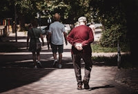 man in red hoodie walking on sidewalk during daytime