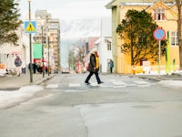 a man walking across a cross walk in the snow