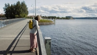 A woman standing on a pier next to a body of water
