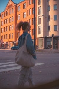 A woman walking across a street in front of a tall building