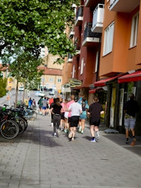 Group of people running down a city sidewalk.