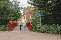 Elderly couple walks across a red bridge.