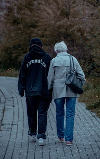 A younger and older person walk together on a path.