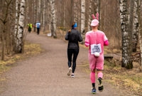 Person in pink bunny costume running on a forest path.