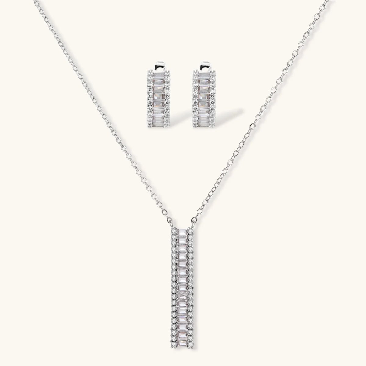 White gold plated necklace with vertical cubic zirconia pendant and matching hoop earrings on neutral background