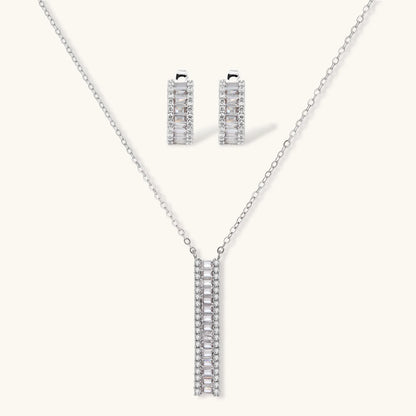 White gold plated necklace with vertical cubic zirconia pendant and matching hoop earrings on neutral background