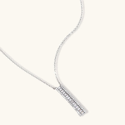 White gold plated necklace with vertical cubic zirconia pendant and matching hoop earrings on neutral background