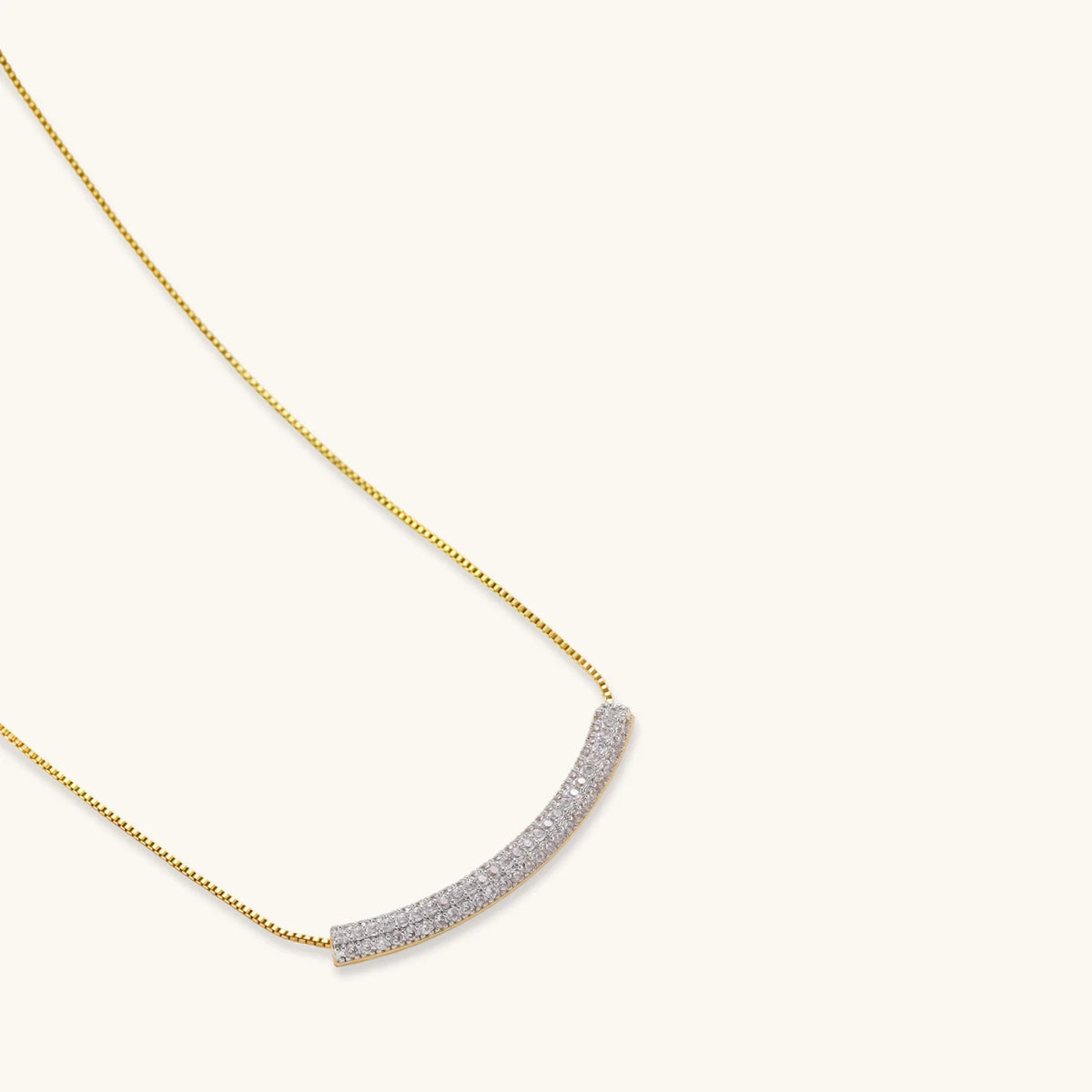Gold-plated curved necklace, hoop earrings, and adjustable ring with pavé cubic zirconia stones on cream background.